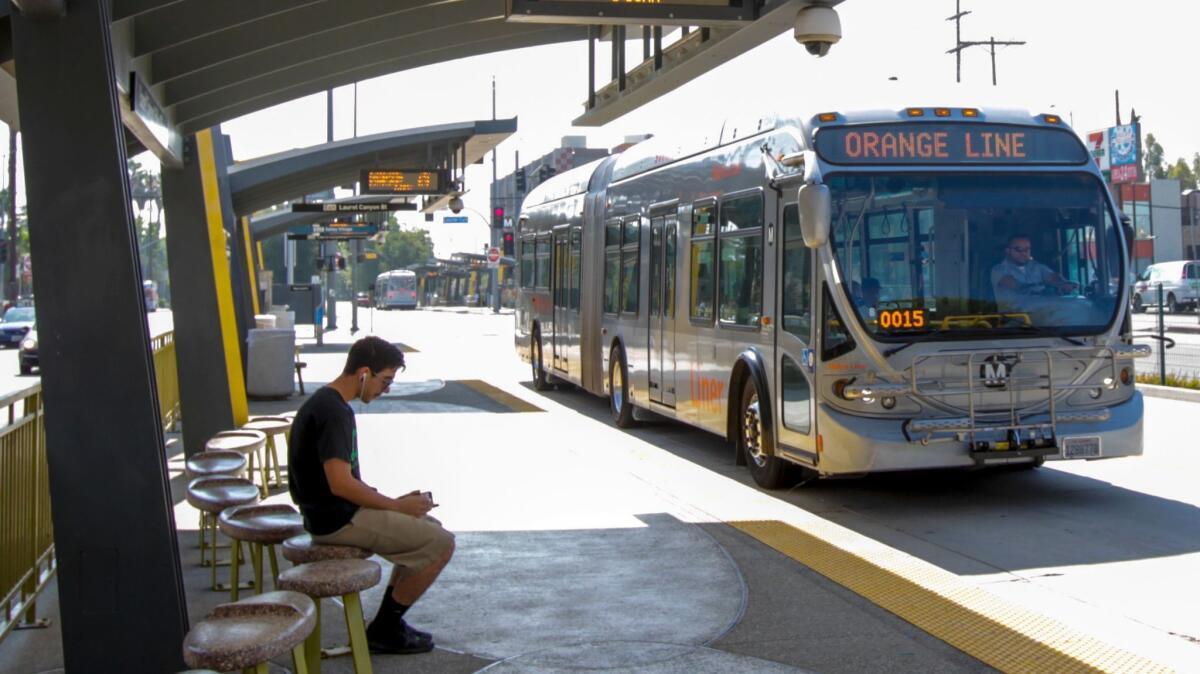A rider waits for an Orange Line bus at the North Hollywood station. The dedicated busway is slated to be the first route in the Metro system to exclusively run electric buses.