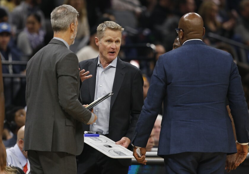 Golden State Warriors head coach Steve Kerr, center, huddles with his assistant coaches during a timeout in the first quarter of an NBA basketball game against the Sacramento Kings in Sacramento, Calif., Monday, Jan. 6, 2020. Kerr was ejected from the game during the second quarter. (AP Photo/Rich Pedroncelli)