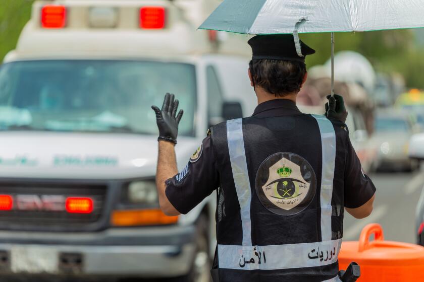 In this July 26, 2020 photo, a Saudi security officer motions to an ambulance at a checkpoint in the Mecca region ahead of the annual hajj pilgrimage. The Islamic pilgrimage has been dramatically downsized this year with only a few thousand residents of Saudi Arabia permitted to take part due to concerns over the coronavirus. (Saudi Ministry of Media)