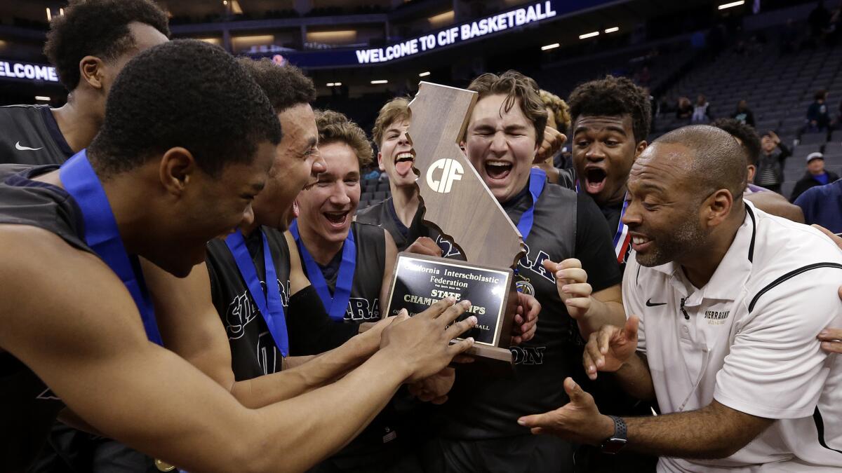 Sierra Canyon coach Andre Chevalier, right, hands the championship trophy to his players after defeating Sheldon 75-62 to win the Open Division state title on March 24.