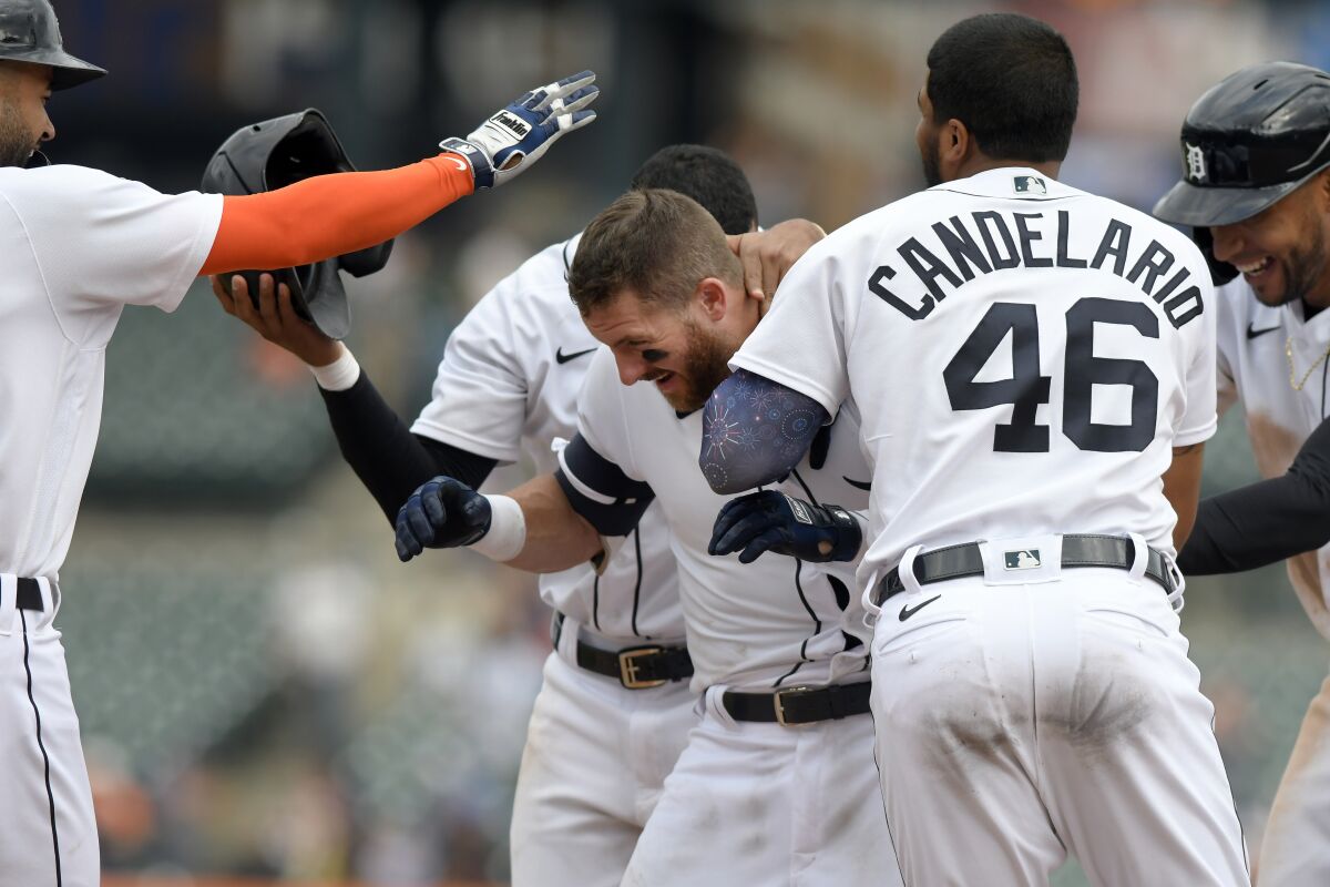 Detroit Tigers' Robbie Grossman, middle, is congratualted by teammates after walking in the winning run with the bases loaded against the Tampa Bay Rays in the eleventh inning of a baseball game, Sunday, Sept. 12, 2021, in Detroit. (AP Photo/Jose Juarez)