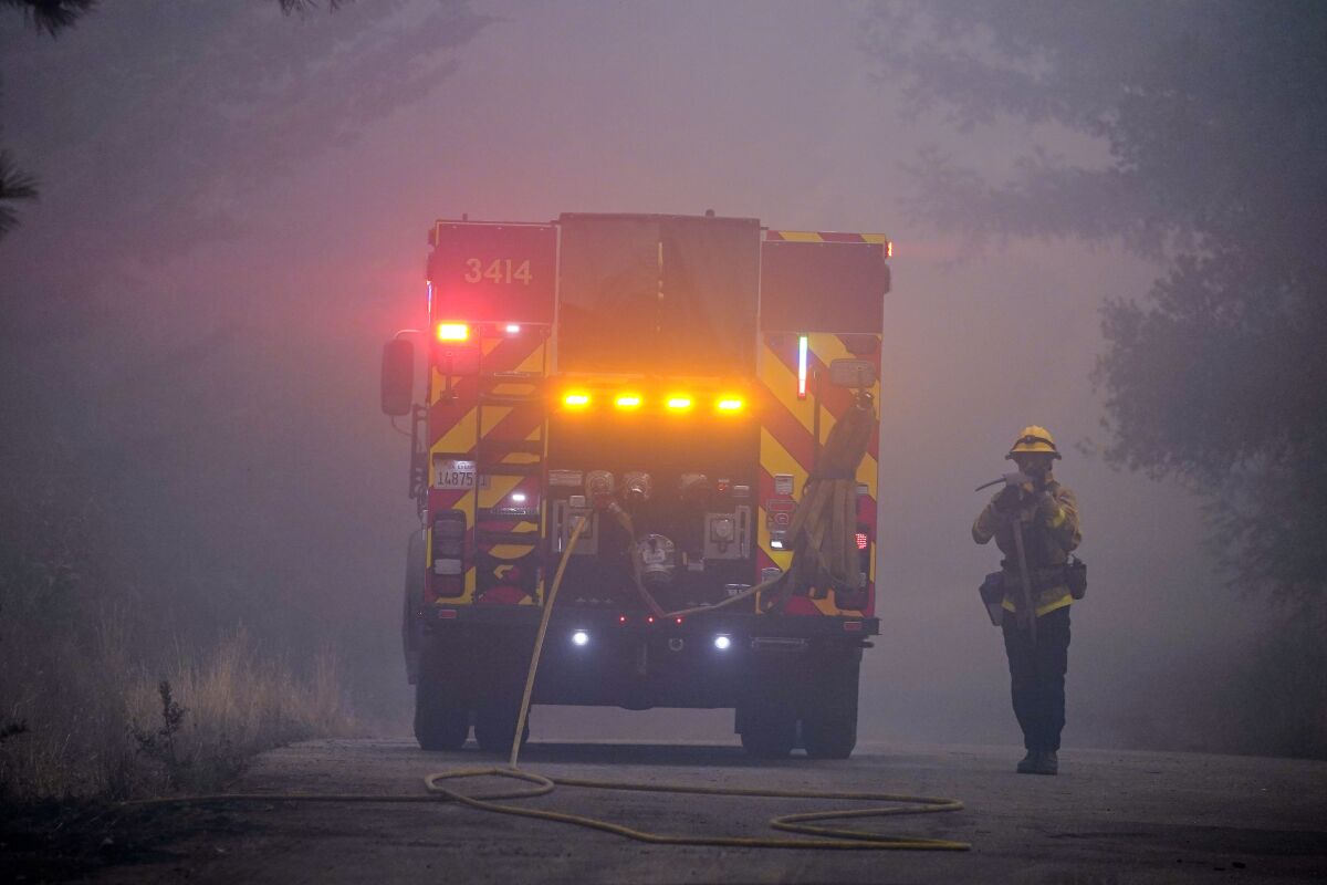 A firefighter walks along a smoke-filled road in Bonny Doon.