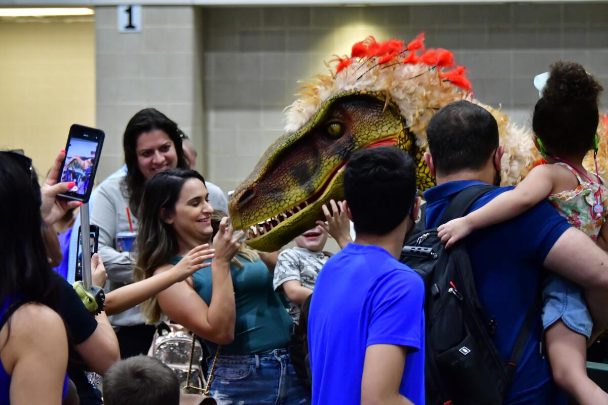 Dinosaur fans interact with a raptor at a Jurassic Quest show.
