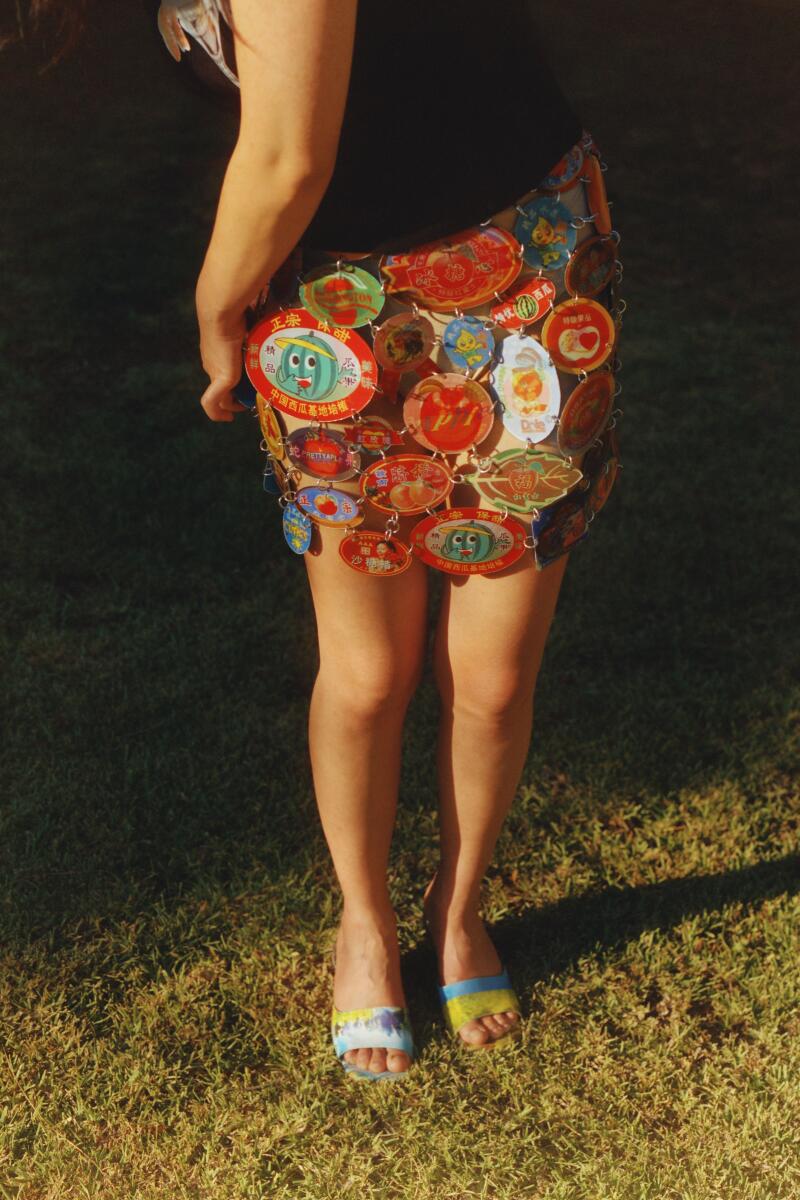 A woman's lower half in black T-shirt and a colorfully patterned short skirt.