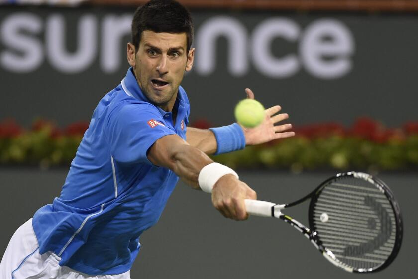 Novak Djokovic reaches to return a shot against John Isner during their match Wednesday night at Indian Wells.