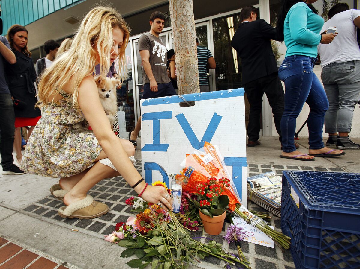 Arrow Denoyer, an 18-year-old freshman, places flowers at a growing memorial in front of the IV Deli on Pardall Road in Isla Vista on Saturday morning. A man was shot and killed at the store in Friday night's rampage.