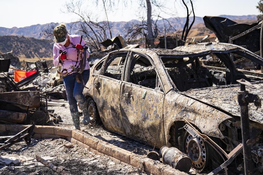 CALIMESA, CA - OCTOBER 17, 2019: Judy Dorius,70, of San Diego salvages iron pot stands from the burned remains of the home where their mother Lois Arvickson, 89, died after the Sandalwood Fire burned her mobile home and many others at the Villa Calimesa Mobile Home Park on October 17, 2019 in Calimesa, California. (Gina Ferazzi/Los AngelesTimes)