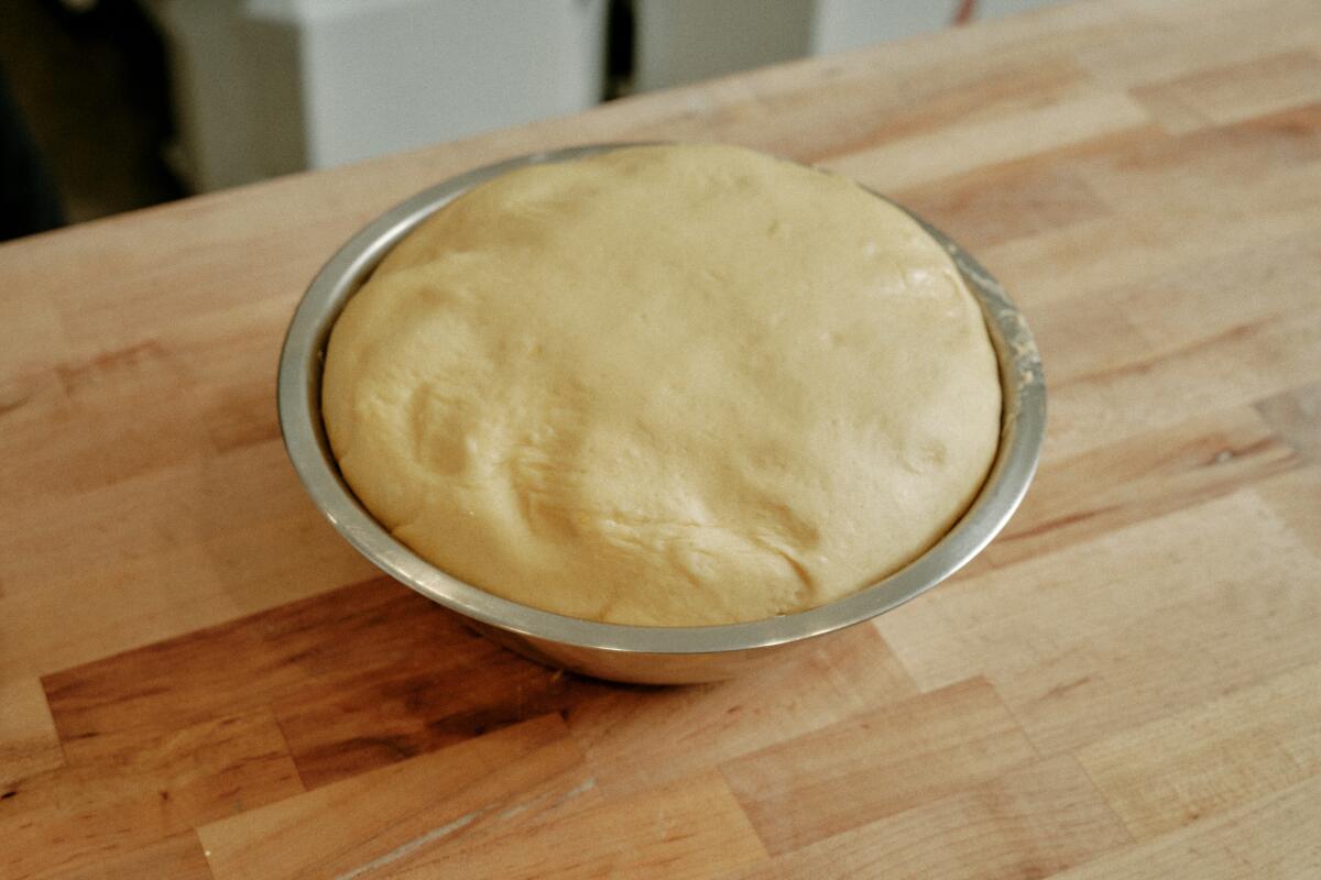 A metal bowl holds a finished dough that has proofed for one hour.