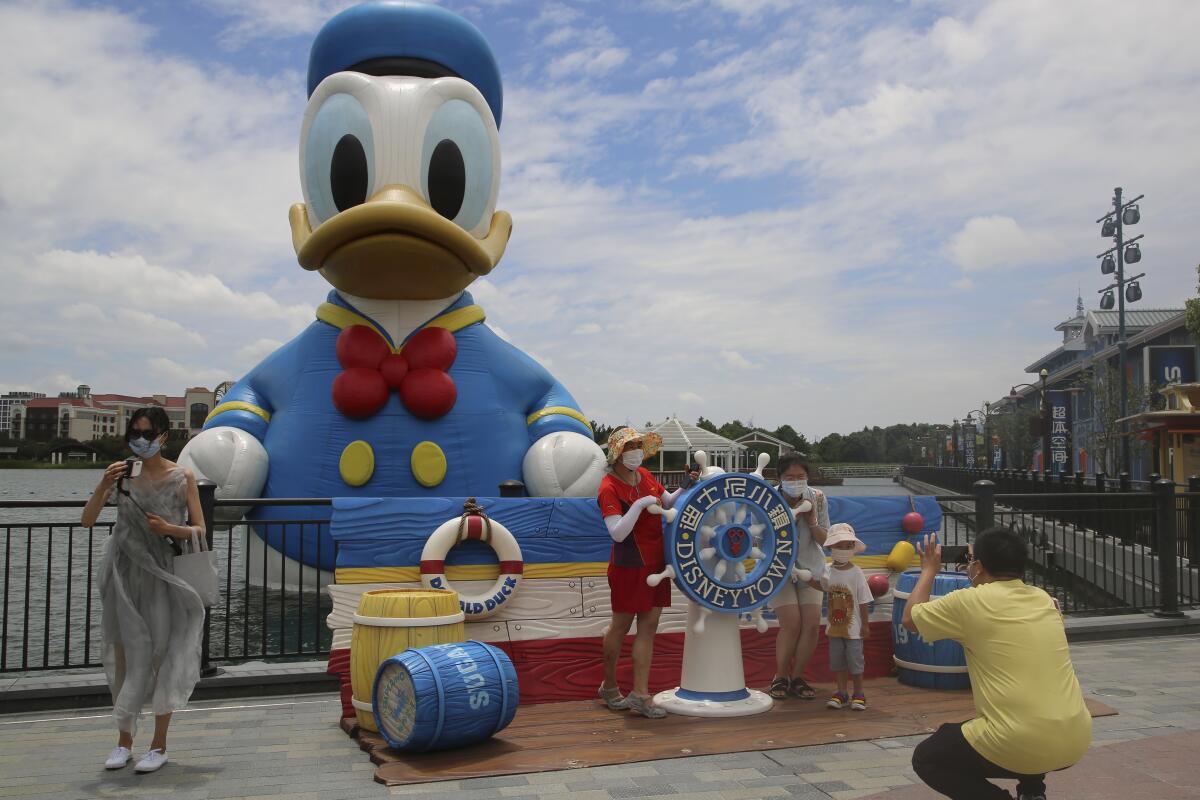 People pose in front of a giant Donald Duck in a body of water.