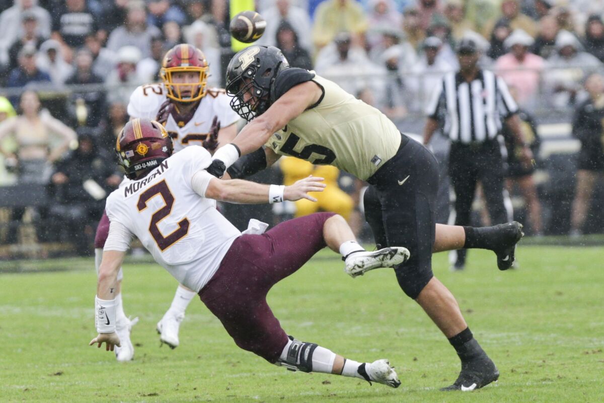 Purdue defensive end George Karlaftis (5) pressures Minnesota quarterback Tanner Morgan (2) during the first quarter of an NCAA college football game, Saturday, Oct. 2, 2021, at Ross-Ade Stadium in West Lafayette, Ind. (Nikos Frazier/Journal & Courier via AP)