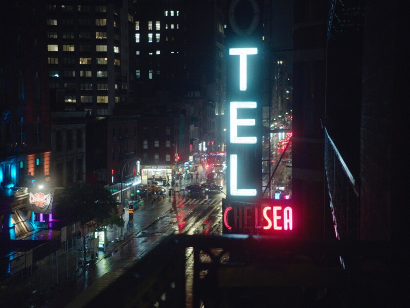 The neon sign for the Chelsea Hotel at night over a wet street in the documentary 