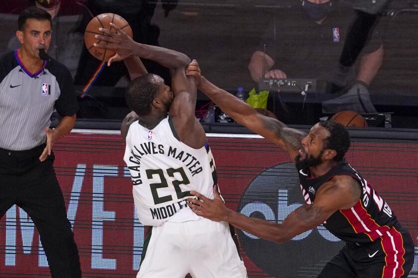 Milwaukee Bucks' Khris Middleton is fouled by Miami Heat's Andre Iguodala during overtime of an NBA conference semifinal playoff basketball game Sunday, Sept. 6, 2020, in Lake Buena Vista, Fla. That's he Bucks won 118-115. The Heat lead the series 3-1. (AP Photo/Mark J. Terrill)