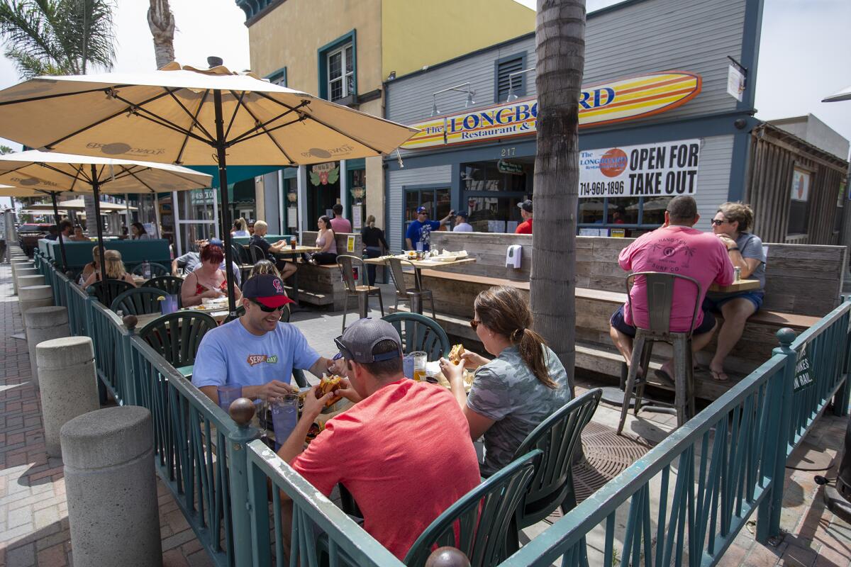 Nick Steffen, left, Mateo Stanford, in red shirt, and Julianne Zenkus eat out at the Longboard Restaurant and Pub in Huntington Beach on Tuesday.