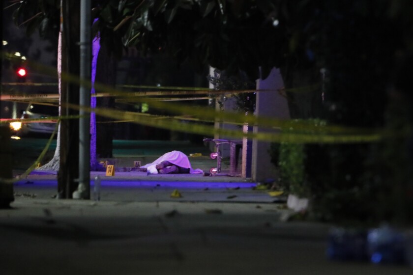 A dead body under a white sheet behind yellow crime scene tape