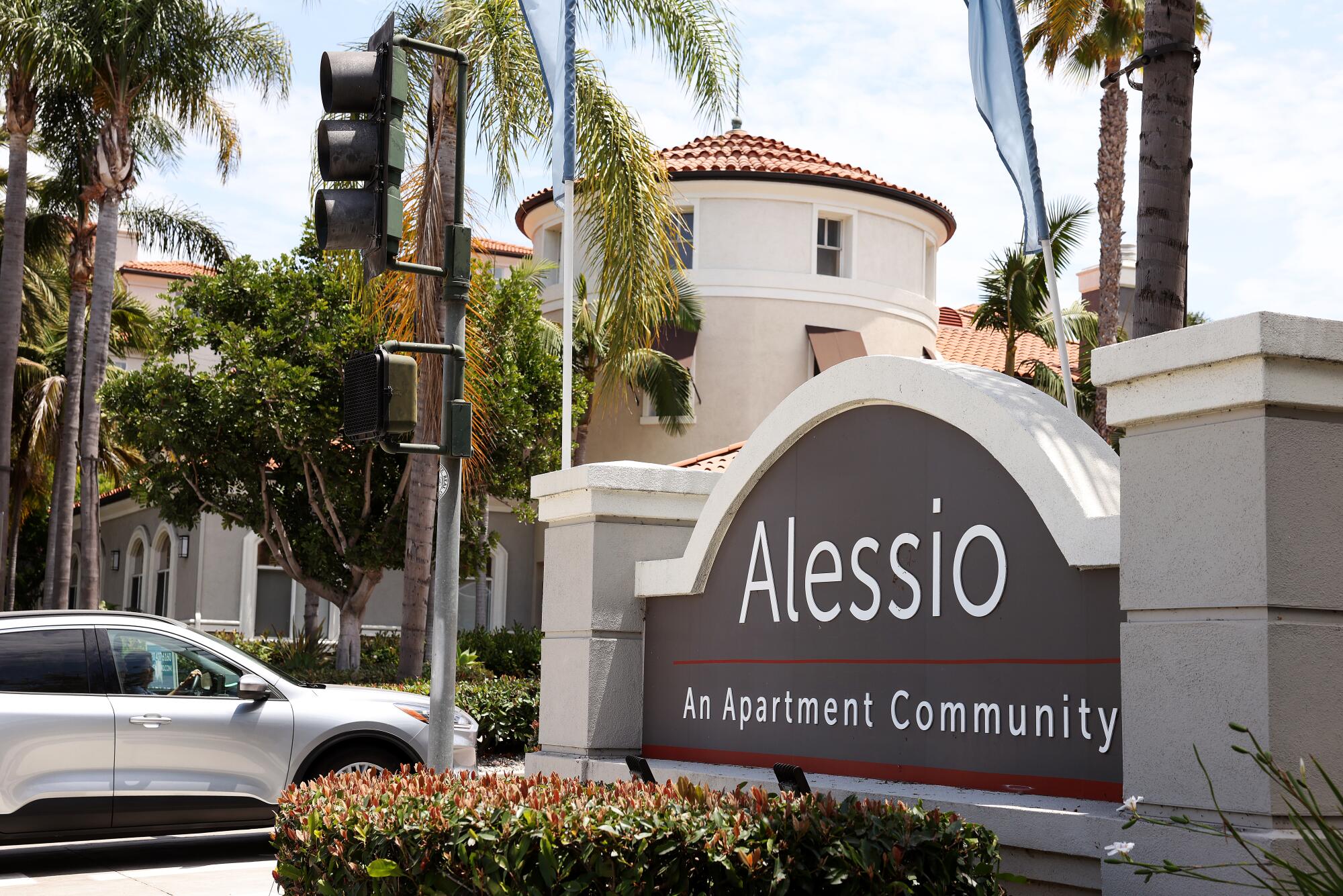 A car passes a sign for the Alessio apartments.