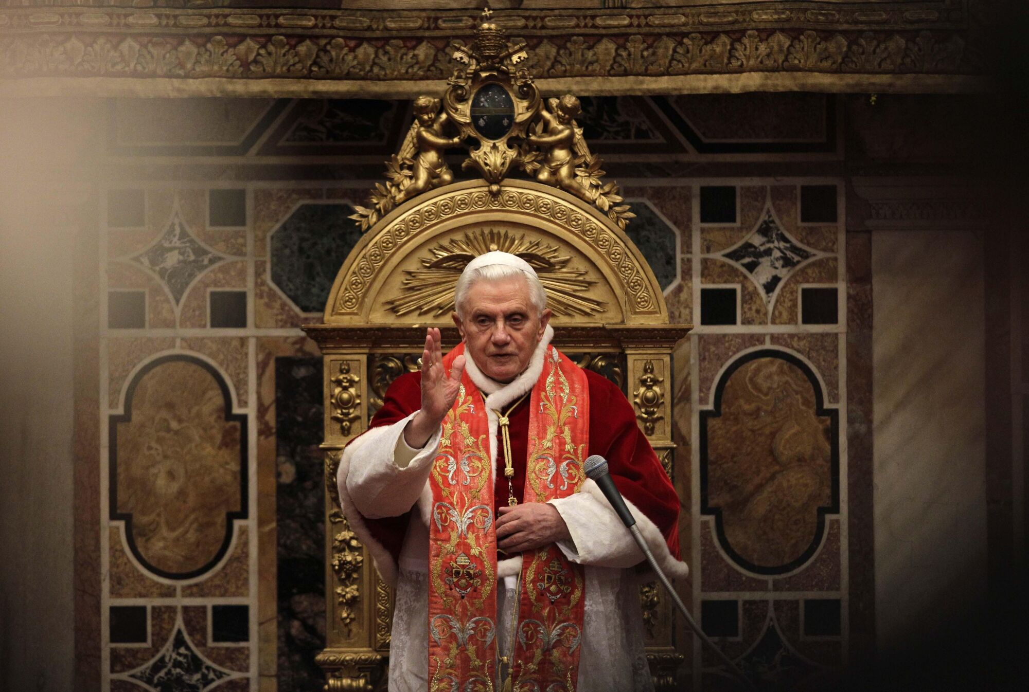 Pope Benedict XVI delivers his blessing while wearing red and white vestments.