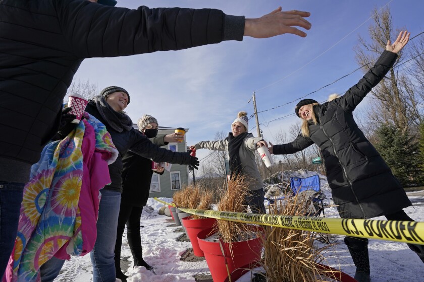 FILE — Canadians Stephanie Frizzell, far right, and her daughter, Shelby Dubois, second from right, move in for a big air hug with their American relatives, Christian Gervais, far left, Sherie Frizzell, second from left, and Caitlin Davis, third from left, after a visit at the U.S.-Canadian border of Stanstead, Quebec and Derby Line, Vt., in this Dec. 19, 2020, file photo. Since shortly after the border closed in March 2020, people from both countries traveled to Derby Line, and Stanstead, to hold impromptu family reunions from their own side of the border on a residential street. It's high summer along the border between the United States and Canada and people on both sides are wondering when the two governments will ease border-crossing restrictions imposed at the beginning of the COVID-19 pandemic. (AP Photo/Elise Amendola, File)