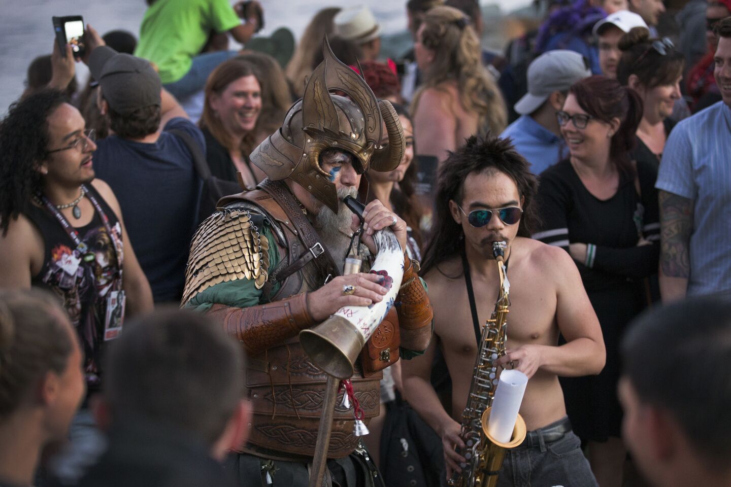 A costumed man blows a Viking horn, accompanied by another man playing the saxophone, at an event promoting the History Channel series "Vikings."