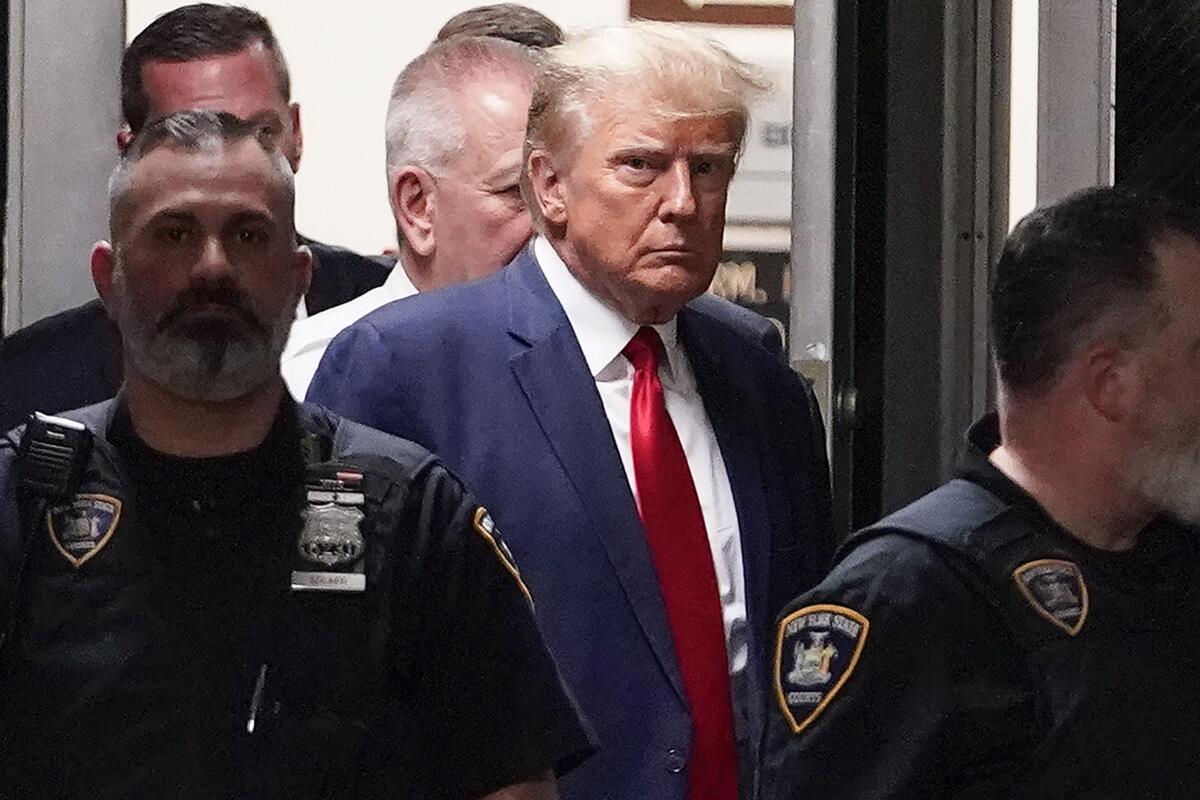 El expresidente Donald Trump es acompañado hacia la sala de un tribunal,