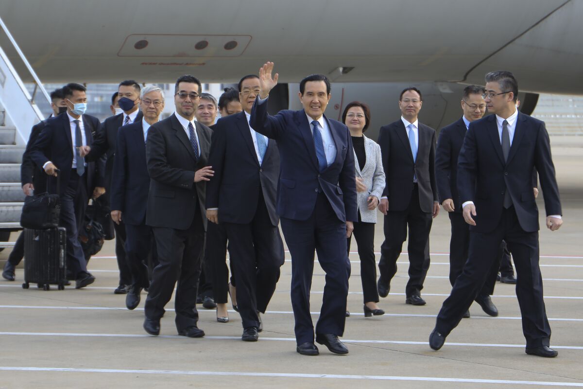 In this photo released by Ma Ying-jeou Office, Former Taiwan President Ma Ying-jeou, center, waves as he arrivers with his delegation at the Pudong airport in Shanghai, China, Monday, March 27, 2023. Ma departed for a tour of China on Monday, in what he called an attempt to reduce tensions a day after Taiwan lost one of its few remaining diplomatic partners to China. Monday, March 27, 2023. (Ma Ying-jeou Office via AP)