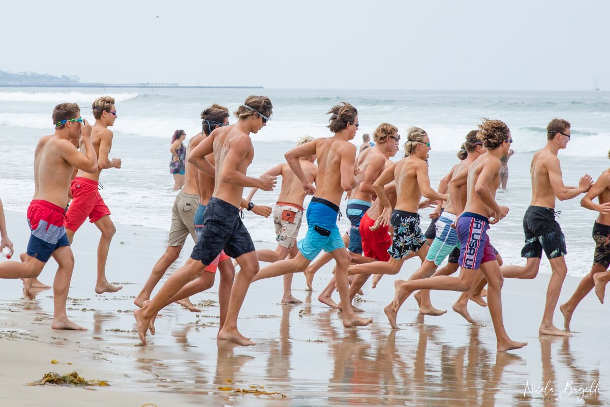 La Jolla High School water polo players run beside the ocean as they train for the new season.
