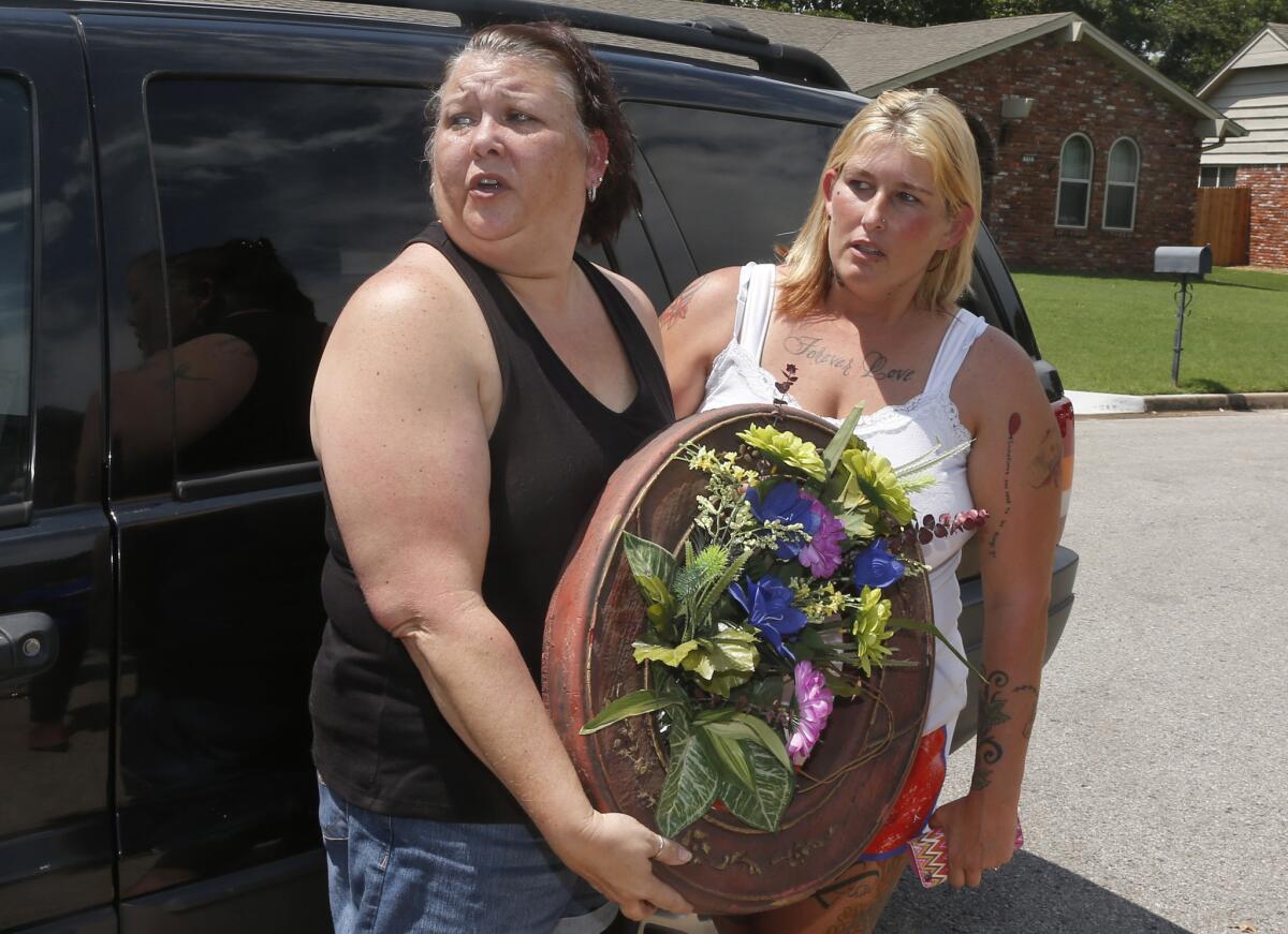 Broken Arrow residents Cindy Rigney, left, and Glenna Parkman arrive with a wreath outside the home where five family members were found dead.