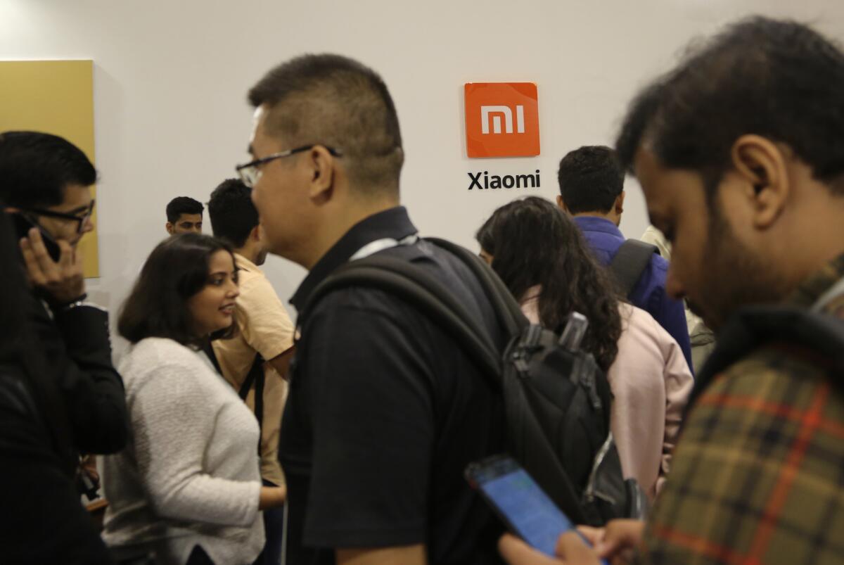 A group of people in a room and the Xiaomi name and logo on a wall 