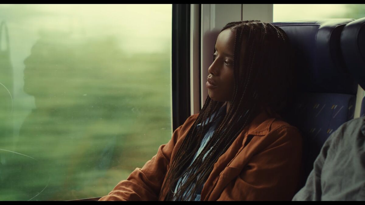 A woman sits in a train car as the world flashes by  in the movie "Saint Omer."