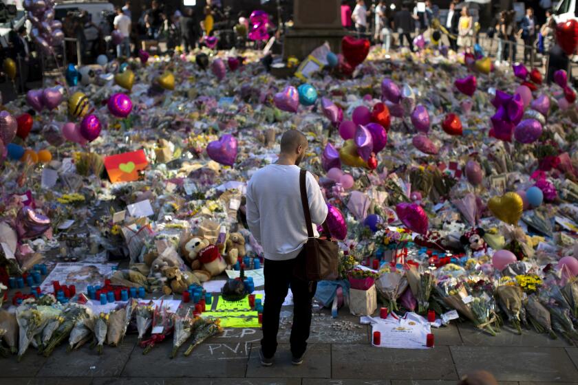 FILE - A man stands next to flowers for the victims of a bombing at St. Ann's Square in central Manchester, England, May 26, 2017. More than 250 survivors of the suicide bombing that killed 22 people at a 2017 Ariana Grande concert in Manchester, England, are taking legal action against Britain's domestic intelligence agency, lawyers said Sunday, April 14, 2024. (AP Photo/Emilio Morenatti, File)