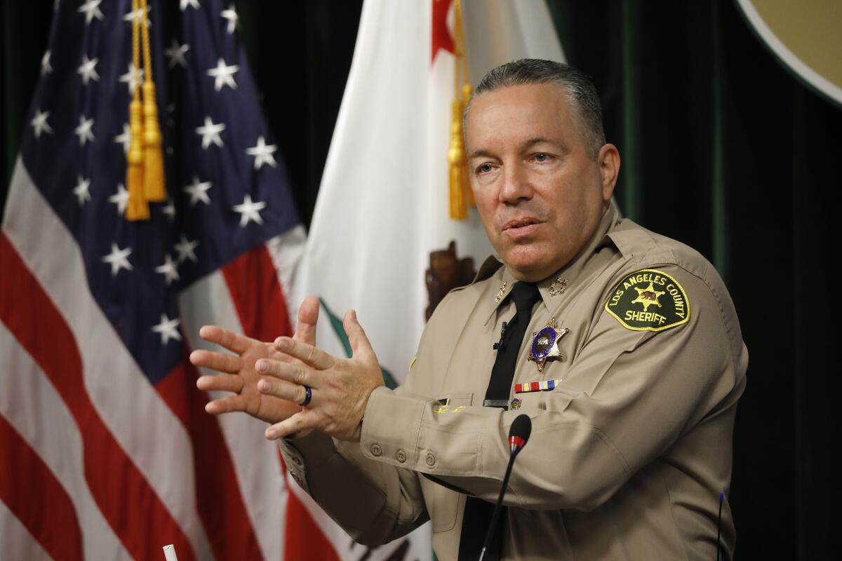 Los Angeles County Sheriff Alex Villanueva speaks next to U.S. and state flags