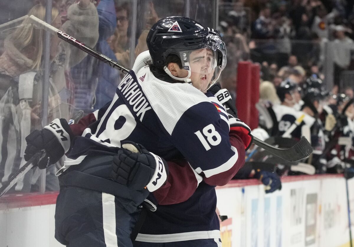 Colorado Avalanche center Alex Newhook, front, is hugged by center Andrew Cogliano after scoring a goal in the first period of an NHL hockey game against the St. Louis Blues, Saturday, Jan. 28, 2023, in Denver. (AP Photo/David Zalubowski)