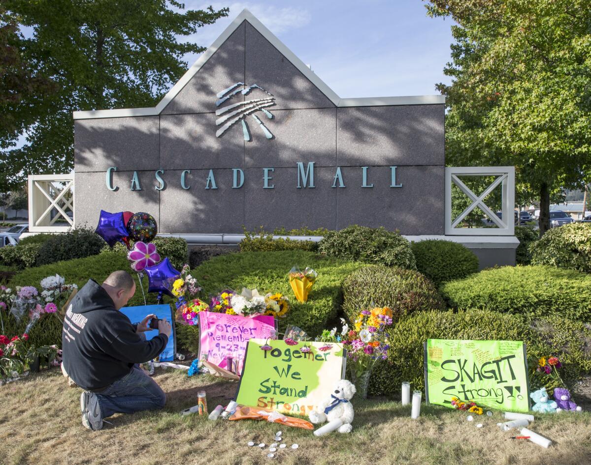 Chris Nelson of Burlington, Wash., takes a picture of a memorial for the five people killed in a shooting rampage at Cascade Mall.