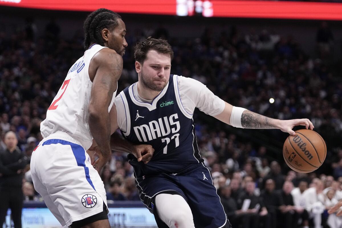 Clippers forward Kawhi Leonard, left, tries to cut off a drive by Mavericks guard Luka Doncic during Game 3 on Friday.