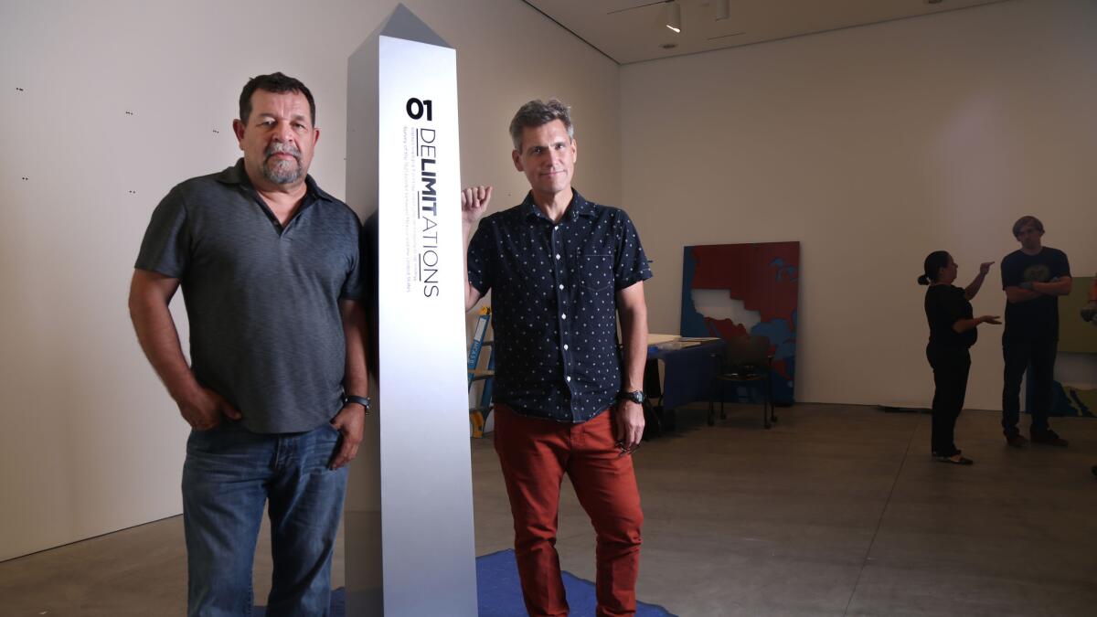 Artists Marcos Ramirez "ERRE," left, and David Taylor, working on the installation of their exhibition "DeLIMITations" at MCASD.