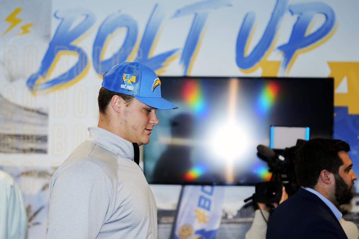 Wearing a Chargers cap, top draft pick Joe Alt arrives to be introduced at a media conference.