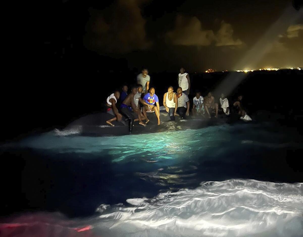 En esta foto proveída por la Real Fuerza de Defensa de Bahamas, se ve a sobrevivientes sobre un bote volcado 