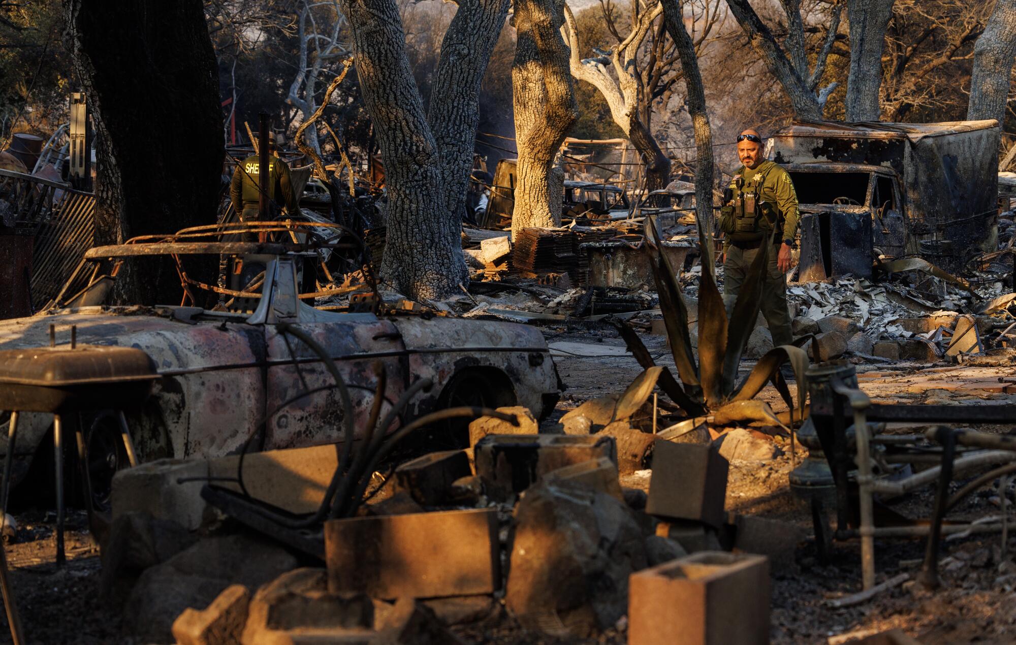 A Riverside County Sheriff deputy walks through area destroyed by the Airport fire off Ortega Highway.