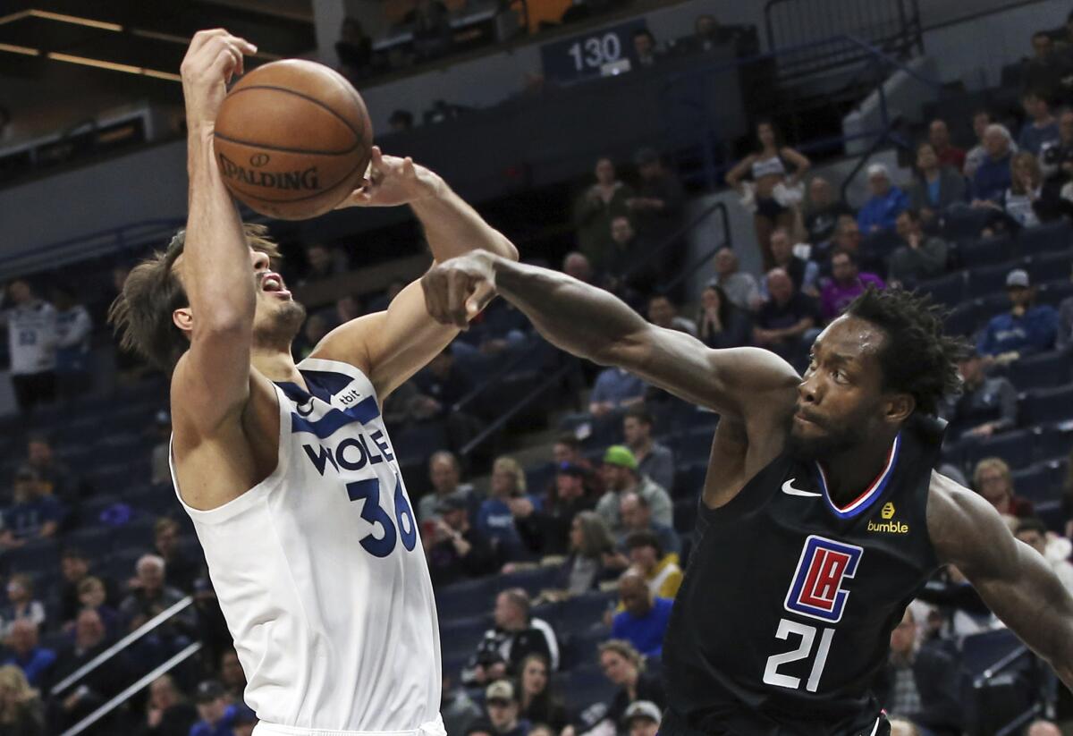 Clippers point guard Patrick Beverley knocks the ball from the grasp of Timberwolves forward Dario Saric during a game.