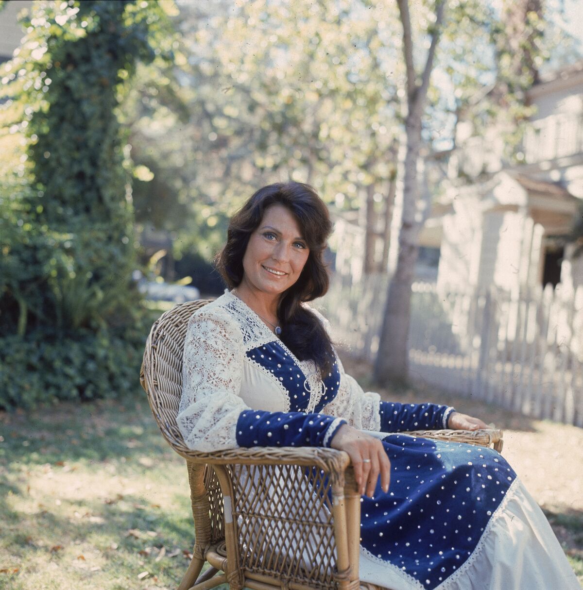 A female country singer sits in a chair outside