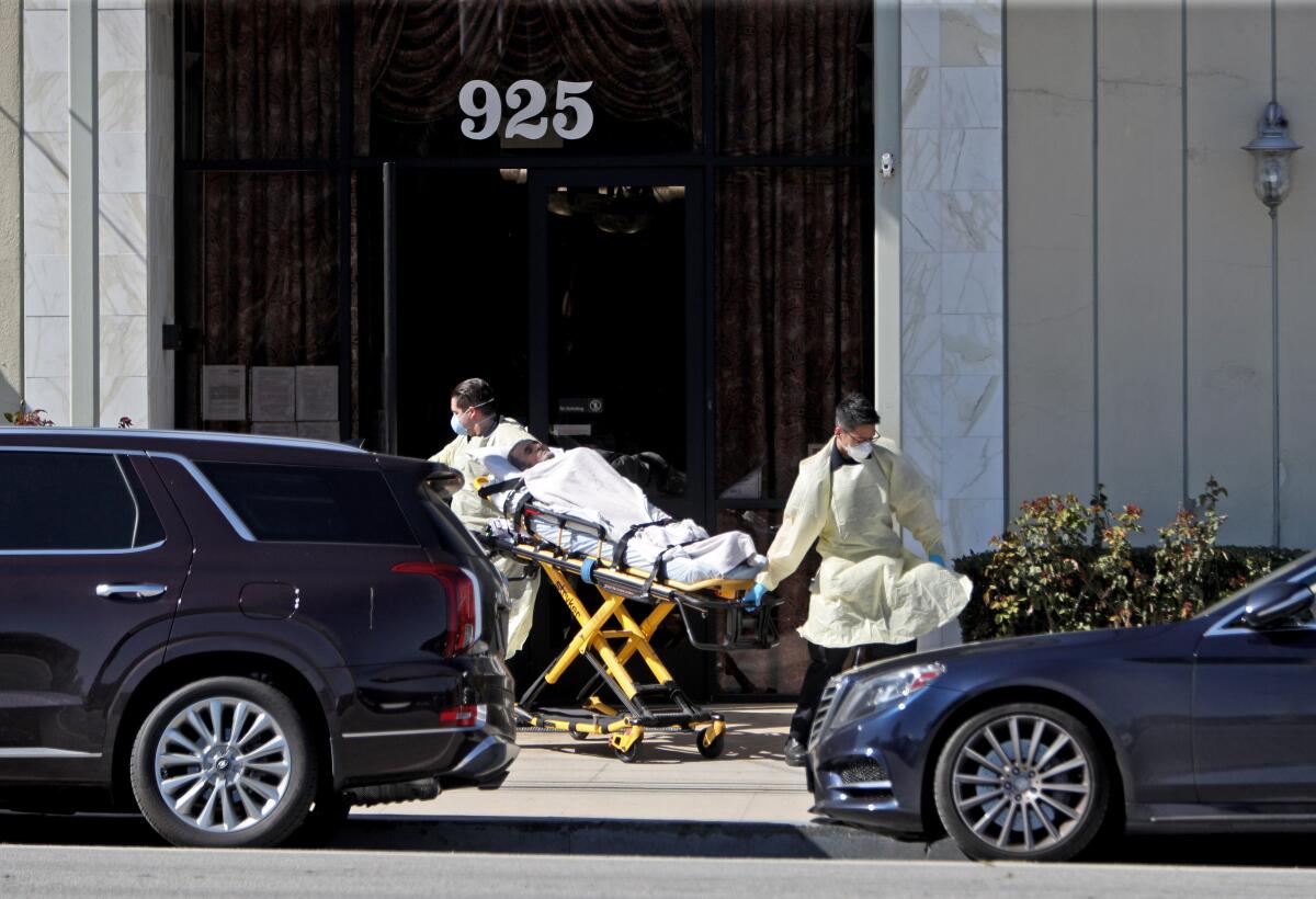 Ambulance emergency medical technicians pick up a patient, whose condition is unknown, from Alameda Care Center on West Alameda Avenue in Burbank on Friday. The center is reporting multiple positive cases of the novel coronavirus that causes COVID-19 among its senior residents.