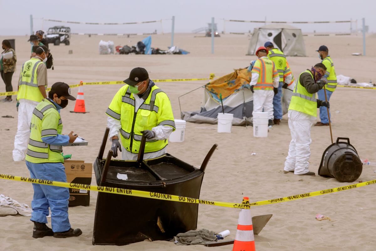 Sanitation workers clear a homeless encampment on the beach