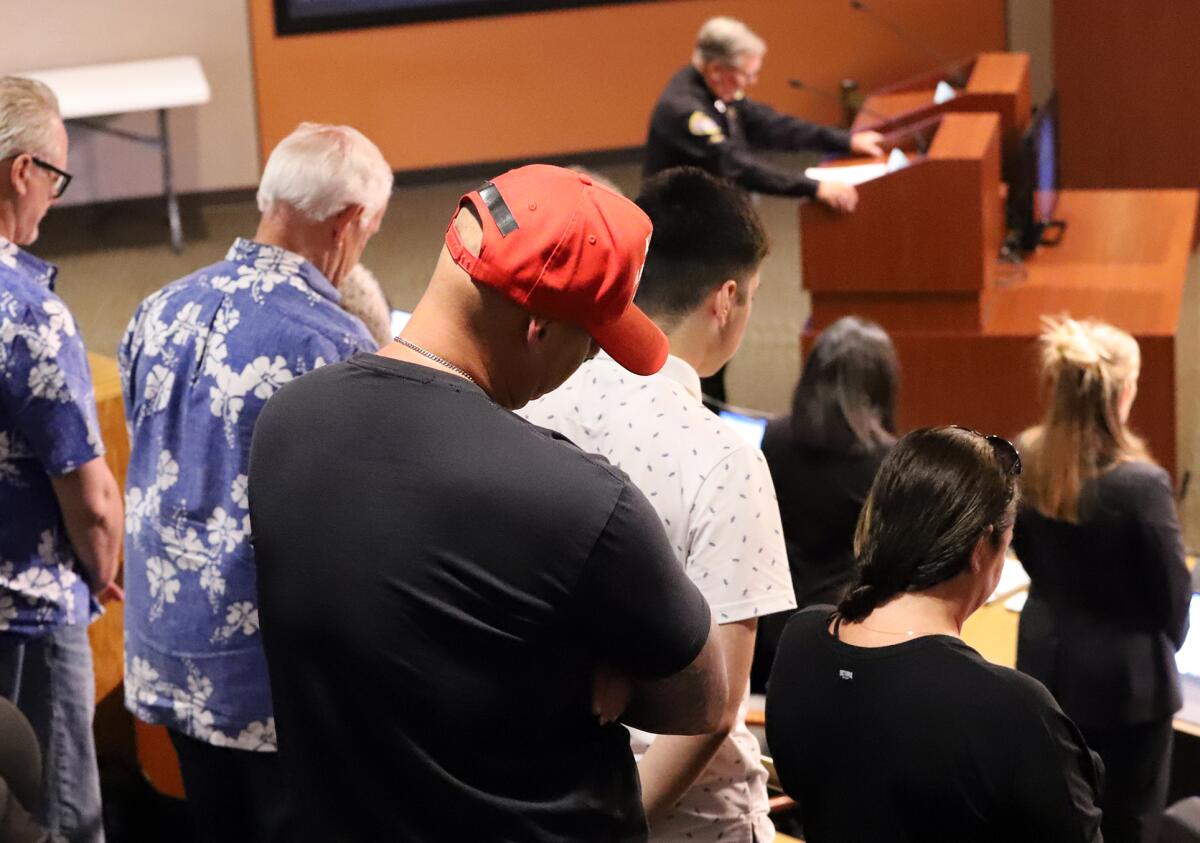 Huntington Beach residents bow their heads as Huntington Beach Police Chaplain Bob Ewing says the invocation Tuesday.