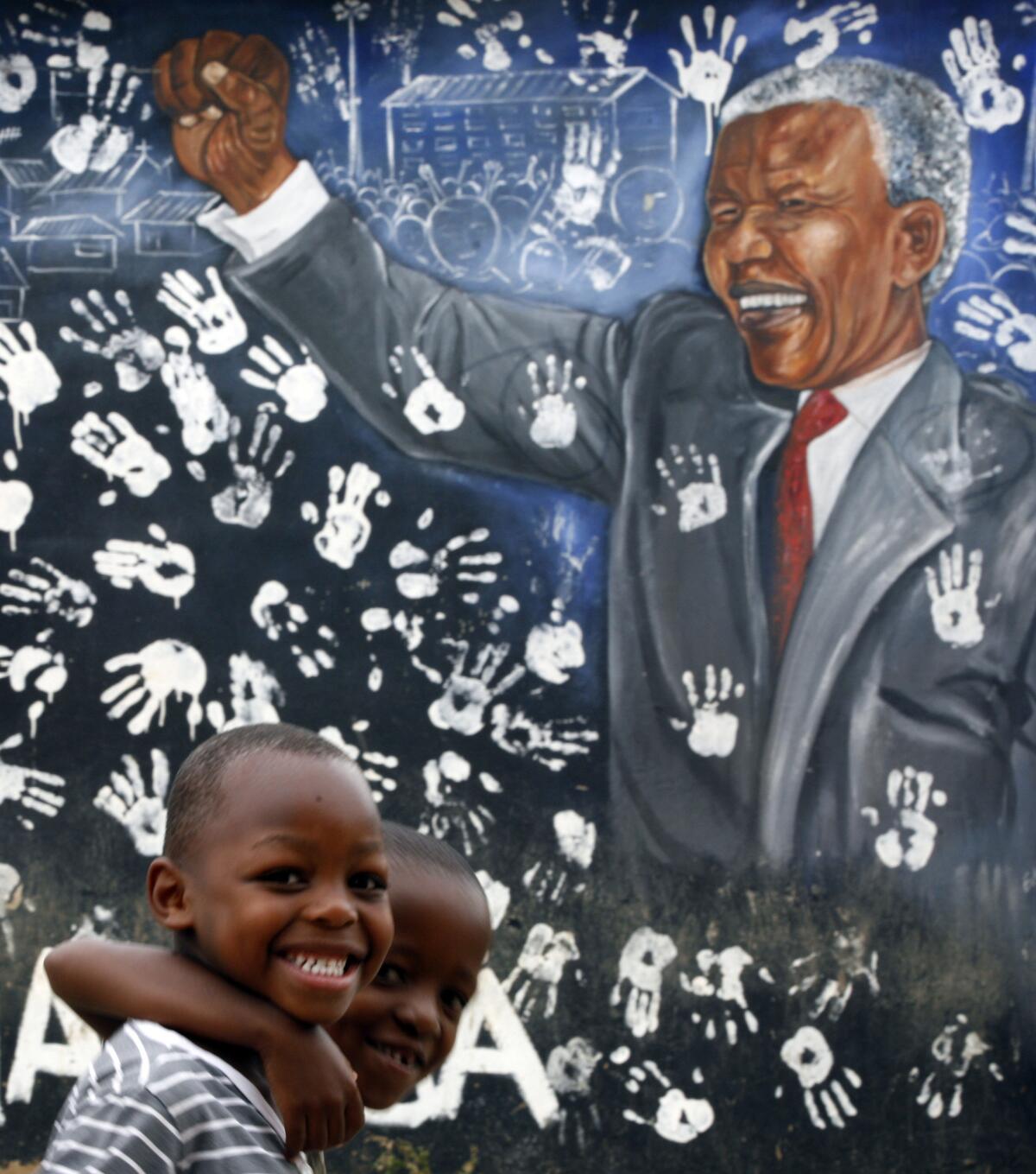 Two boys walk past a mural depicting former South African President Nelson Mandela at the Alexandra township in Johannesburg, South Africa. Mandela died at the age of 95 on Thursday.