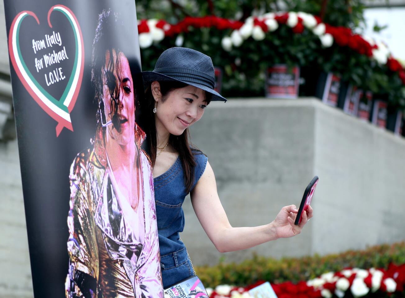 Eriko Ono, 49, of Tokyo takes a selfie with a poster as hundreds of Michael Jackson fans gathered at Forest Lawn Cemetery in Glendale to pay tribute on the 10th anniversary of the death of the King of Pop on June 25, 2019.