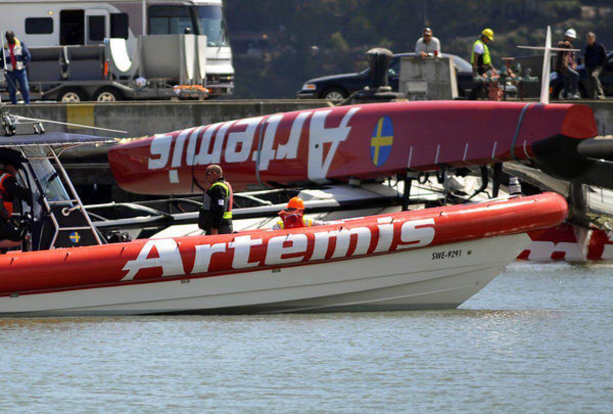 Artemis crew members continue operations to remove their damaged boat from San Francisco Bay off Treasure Island on Thursday.