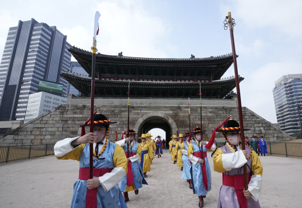Performers wearing traditional guard uniforms and face masks march during a reenactment of opening and closing of the gate at the Sungnyemun Gate in Seoul, South Korea, Tuesday, March 15, 2022. South Korea had its deadliest day yet of the pandemic on Tuesday as the country grapples with a record surge in coronavirus infections driven by the fast-moving omicron variant. (AP Photo/Ahn Young-joon)