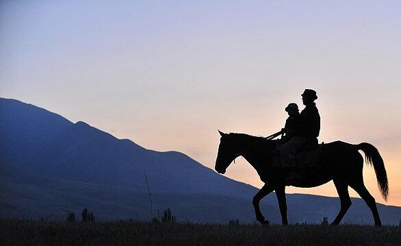 A man rides with a child at sunset.