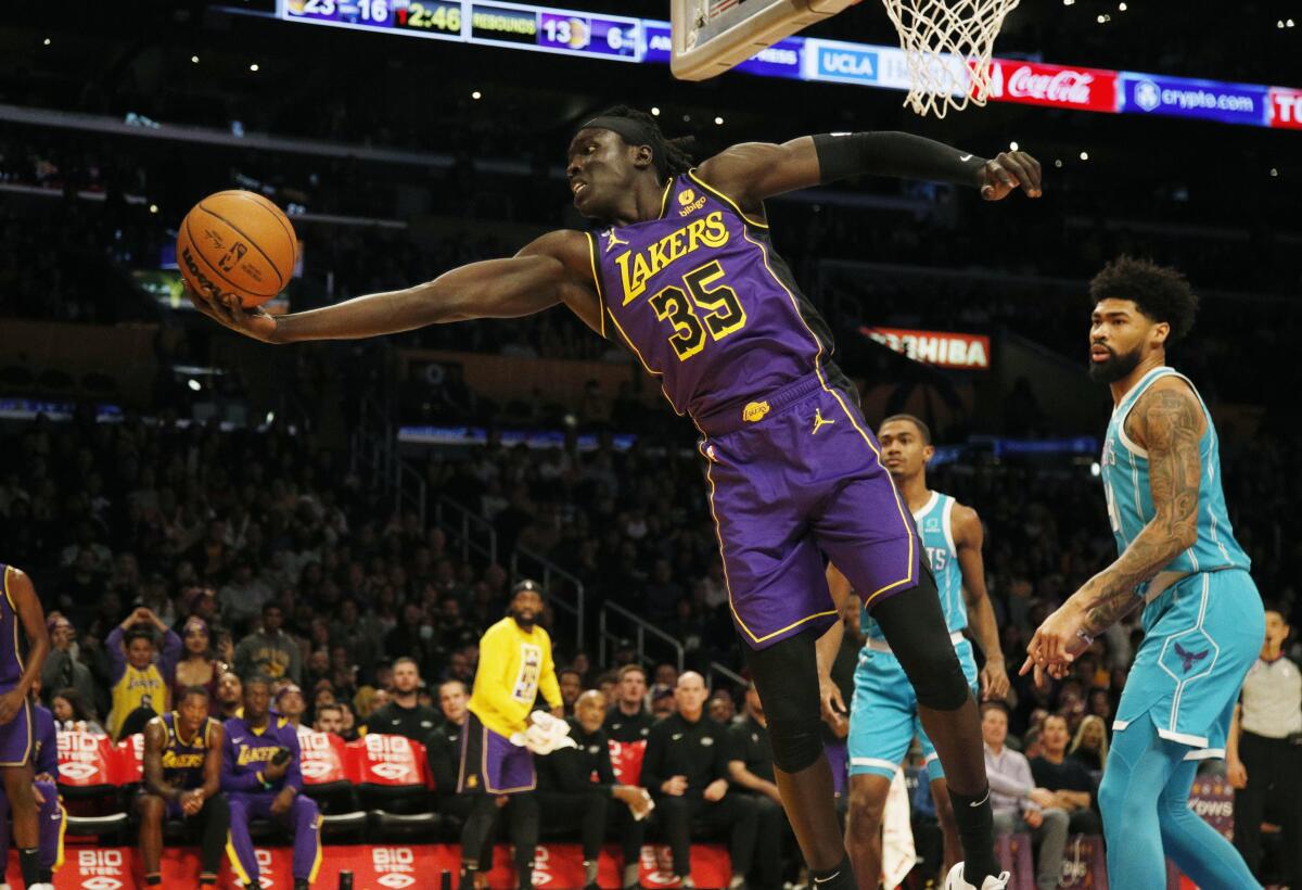Lakers forward Wenyen Gabriel saves a ball from going out of bounds in front of Charlotte Hornets center Nick Richards,