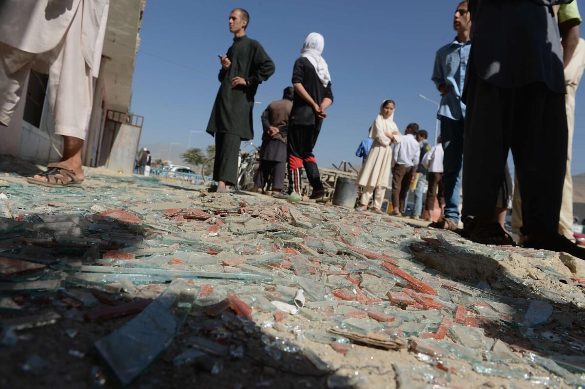 Afghan men look on amid broken glass and debris at the site of a suicide attack in Kabul on July 22.