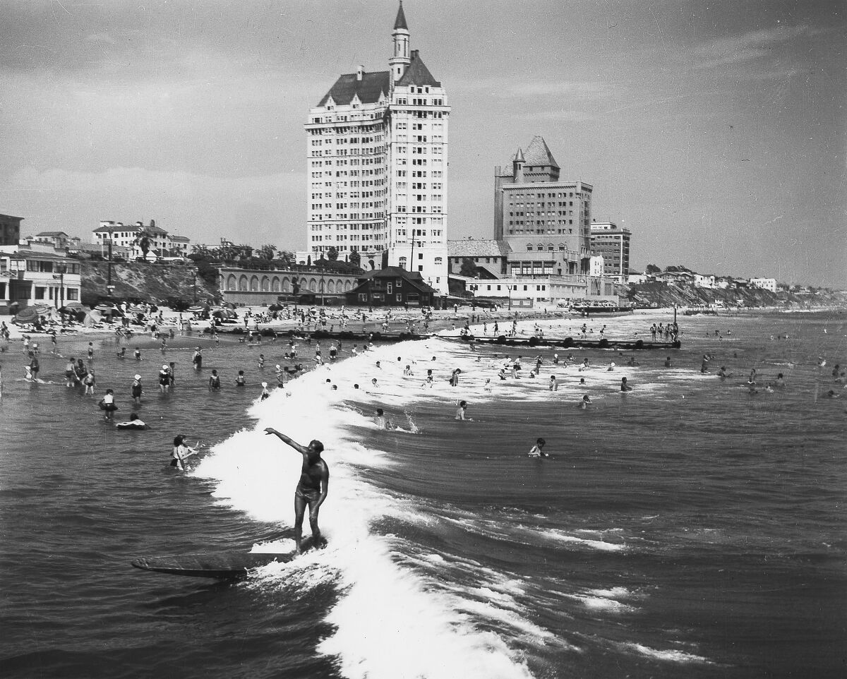 An image from 1938, before the breakwater was constructed, shows a surfer riding a wave in Long Beach.